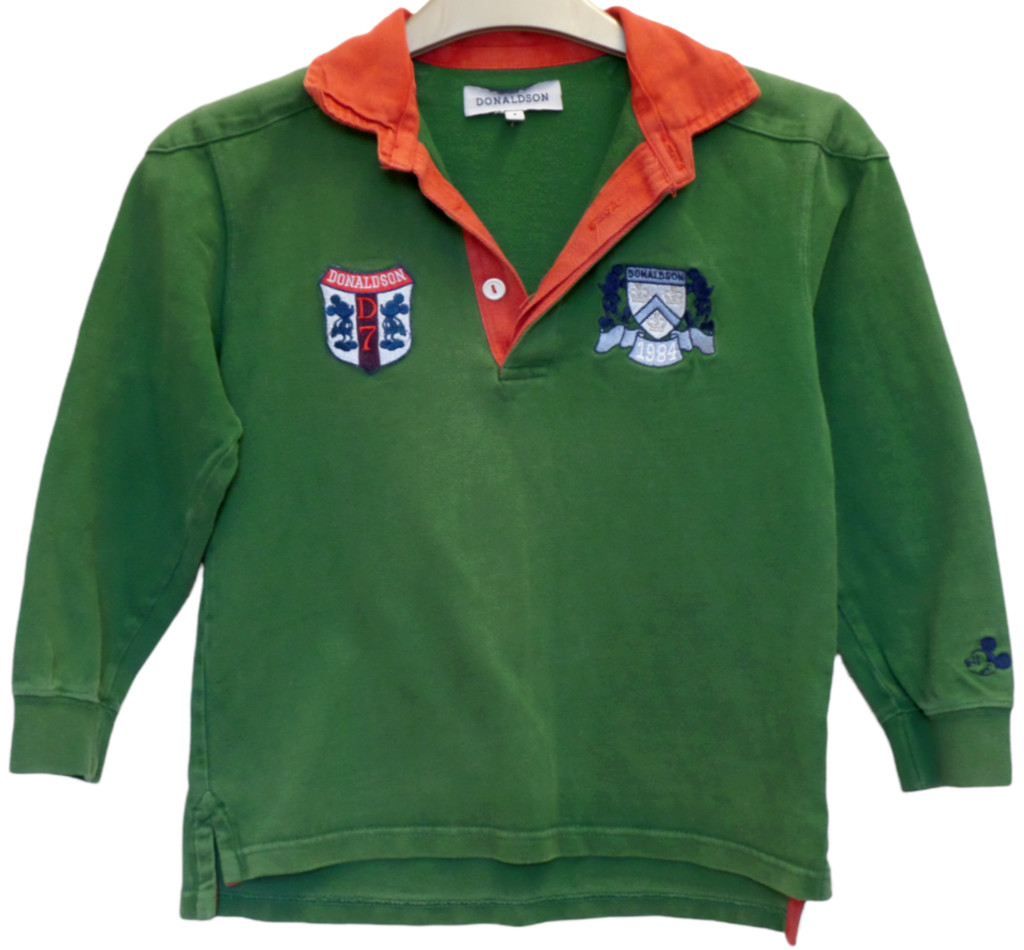 A green polo shirt featuring fictional Donaldson collegiate heraldry